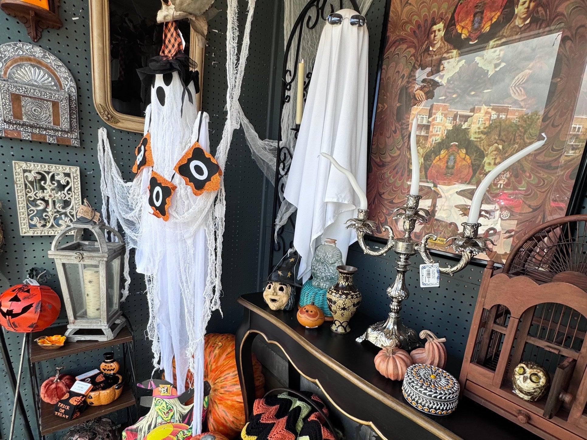 Halloween vignette in a dealer booth at Jackson Square Collective, with two white ghosts, a BOO banner, a silver candelabra, a vintage witch figure, owl figurines, pumpkins and a chevron crochet afghan | Jackson Square Collective in La Grange Park, IL