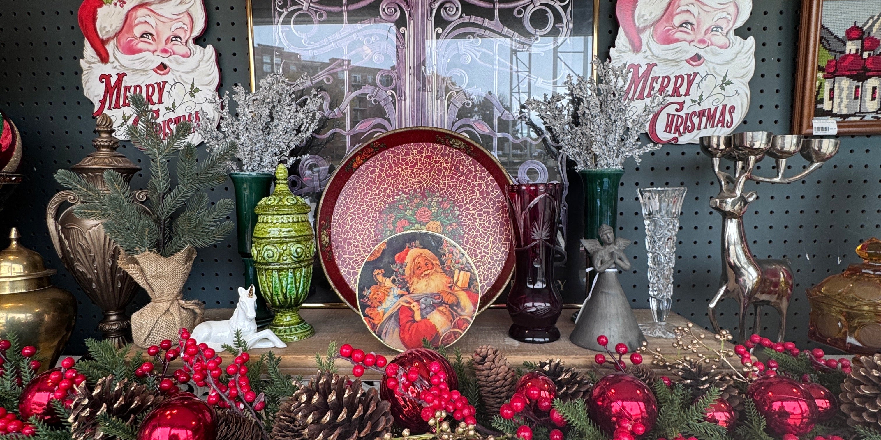 Vintage Christmas display at Jackson Square Collective with Merry Christmas Santa die-cuts, a Santa tin, ruby and crystal glass vases, a green ceramic urn and red berry garland. | Jackson Square Collective in La Grange Park, IL