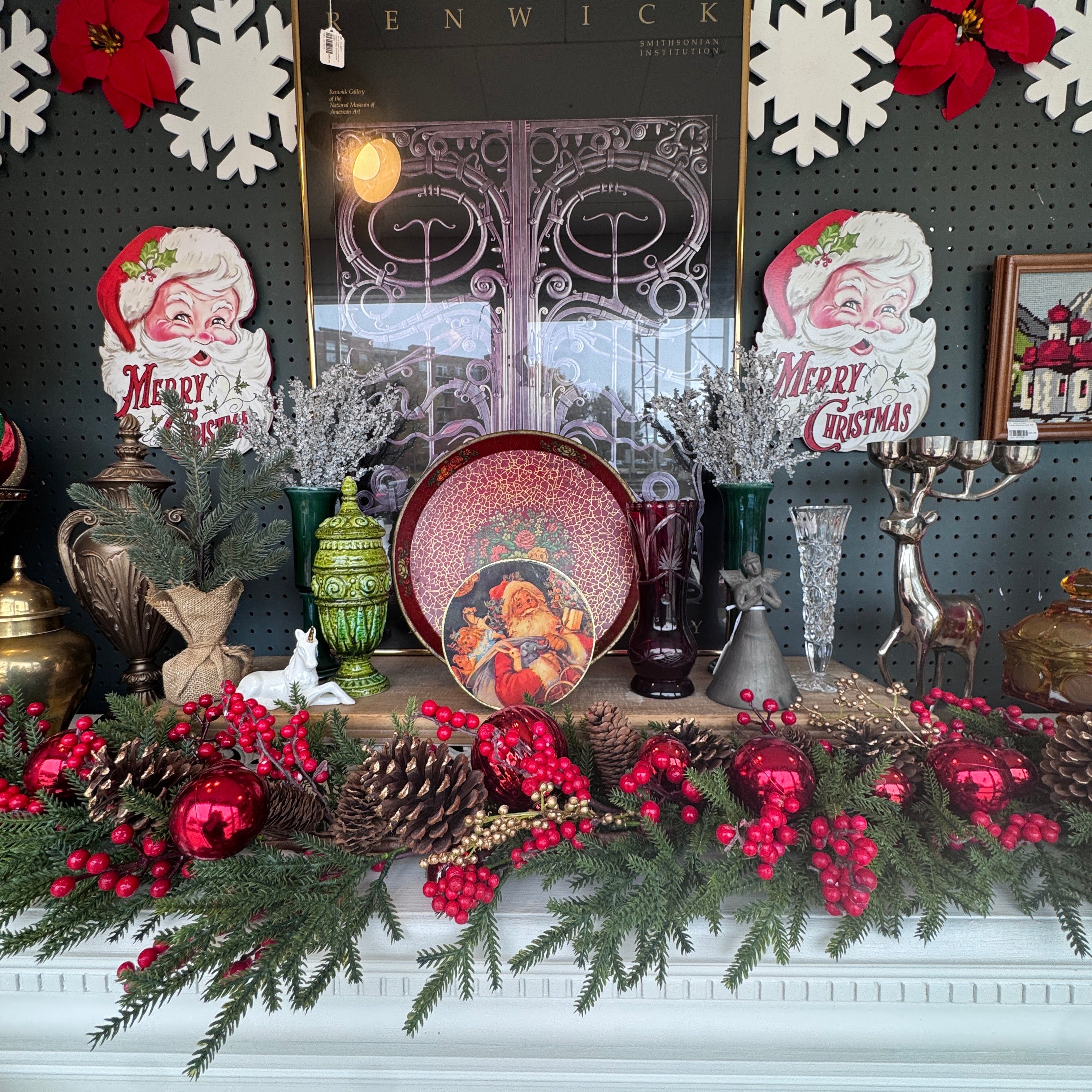 Vintage Christmas display at Jackson Square Collective with Merry Christmas Santa die-cuts, a Santa tin, ruby and crystal glass vases, a green ceramic urn and red berry garland. | Jackson Square Collective in La Grange Park, IL
