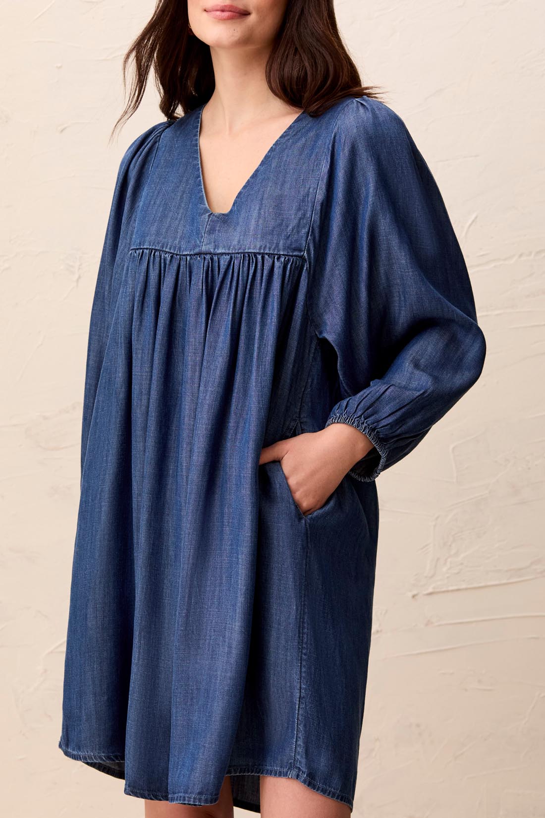 Puff sleeve dress in medium wash with a V-neckline and pockets, made of denim-like fabric.