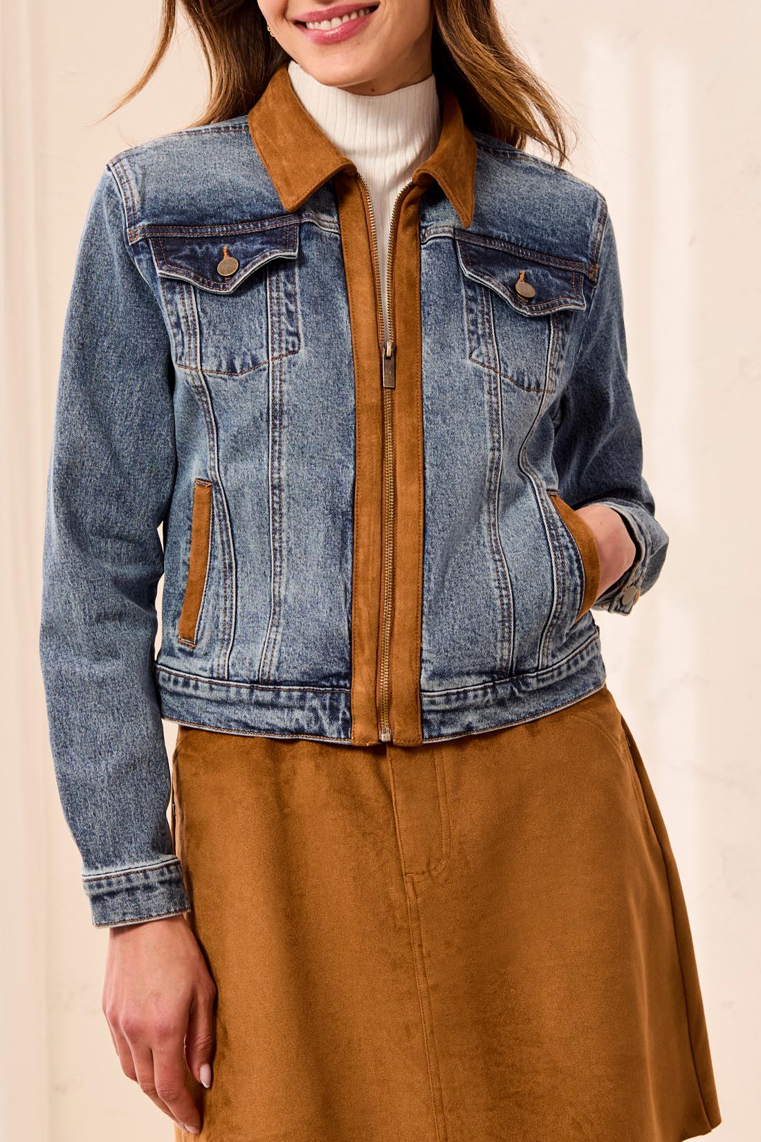 Medium wash denim jacket with suede accents and zip front closure, worn over a white turtleneck.
